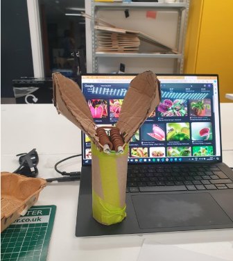 A cardboard prototype of two petals next to a laptop showing flytrap photos.
