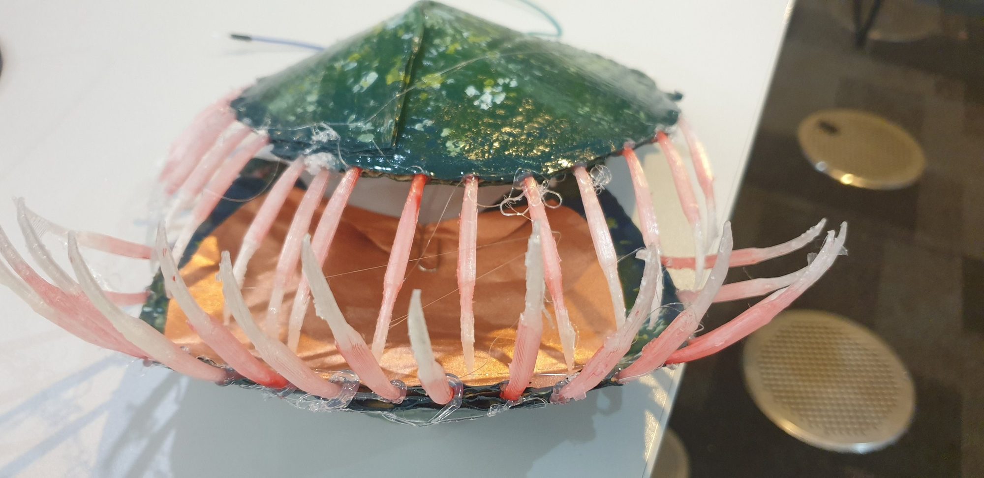 Close-up of the sculpture's petals: dark green outside, copper pad inside, rows of pink 3D-printed teeth.